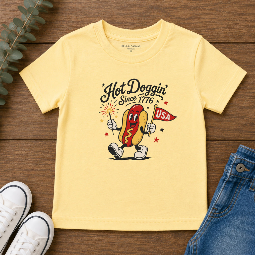 Hot Doggin Since 1776 Tee, Patriotic USA Hot Dog Shirt, Funny Summer Cartoon Graphic Top, Fourth of July Celebration Outfit Toddler Short Sleeve Tee